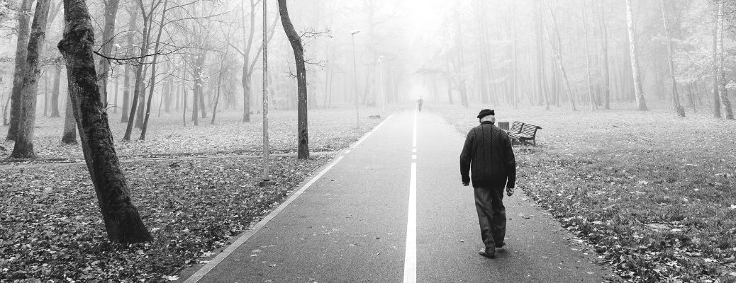 An old man waling on a road alone