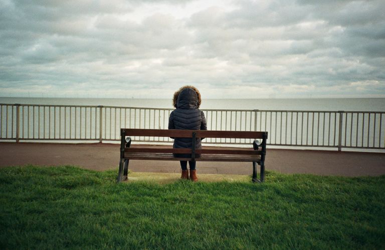 A lady sitting on a bench worried