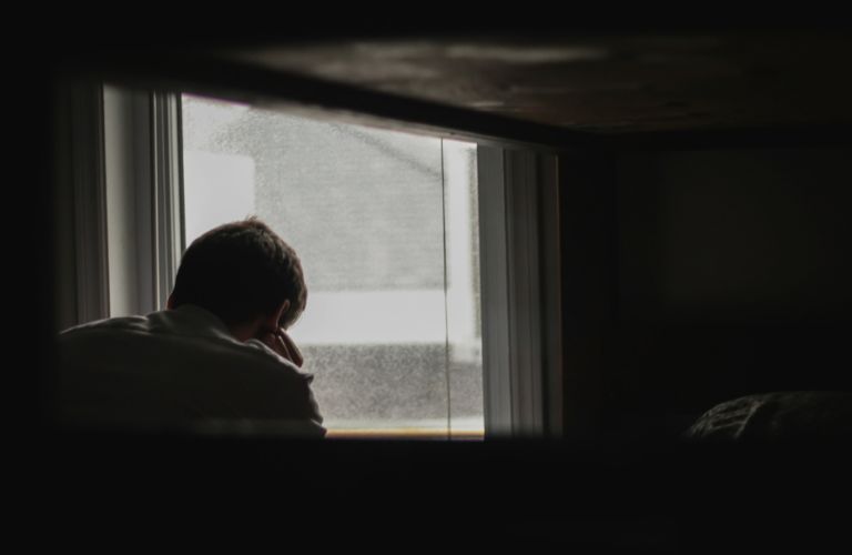 A man standing near a window worried